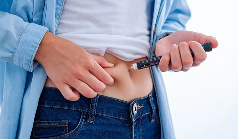 Person injecting insulin into abdomen.