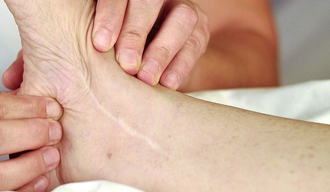 Hand applying pressure on ankle.